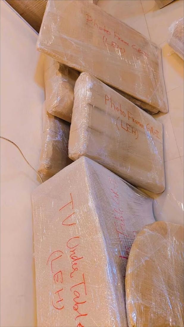 Household items wrapped and clearly labelled by hand, including photo frames and a TV table, ready for household shifting